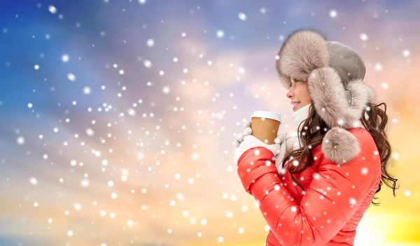 Mulher no chapéu de pele de inverno com café sobre a neve — Fotografia de Stock