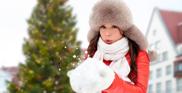 Woman blowing to snow over christmas tree — Stock Photo, Image