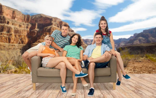 Friends sitting on sofa over grand canyon — Stock Photo, Image