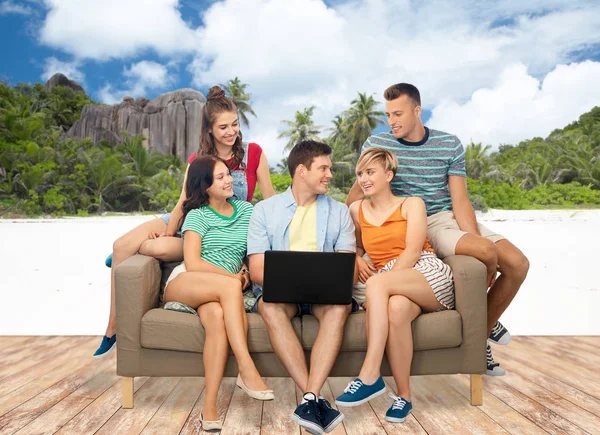 Друзья с ноутбуком сидят на диване над пляжем — стоковое фото