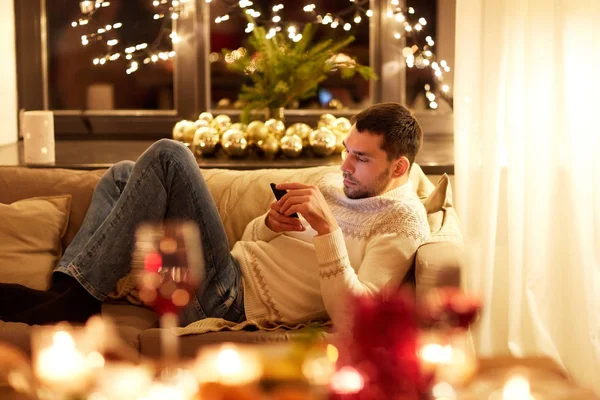 क्रिसमस की पूर्व संध्या पर घर पर स्मार्टफ़ोन के साथ आदमी — स्टॉक फ़ोटो, इमेज