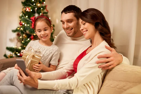 Rodina s smartphone doma na Vánoce — Stock fotografie