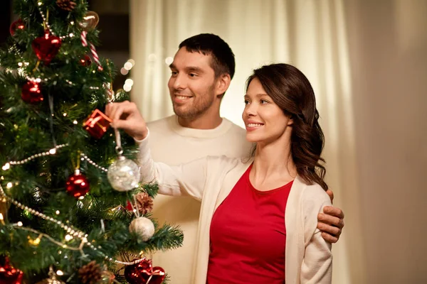 幸せなカップル飾るクリスマスツリー自宅で — ストック写真