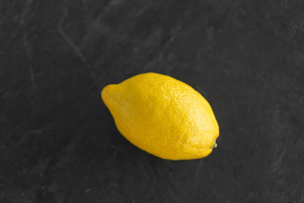 Close up of whole lemon on slate table top — Stock Photo, Image