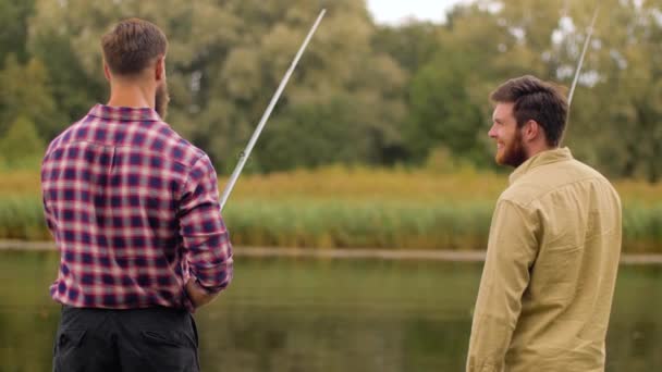 Gelukkige vrienden met hengels op lake — Stockvideo