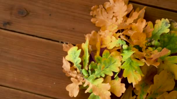 Hojas de roble en colores otoñales sobre mesa de madera — Vídeos de Stock