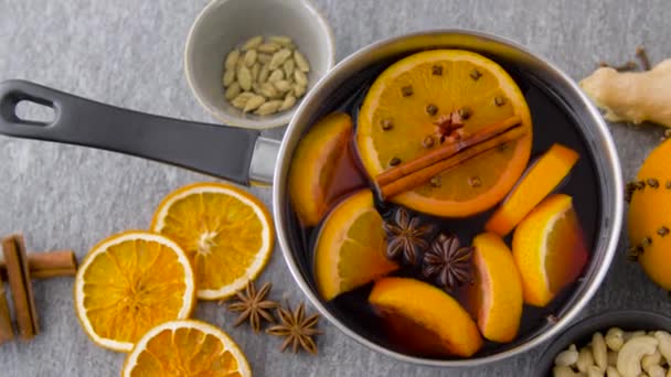 Pot with hot mulled wine, orange slices and spices — Stock Video