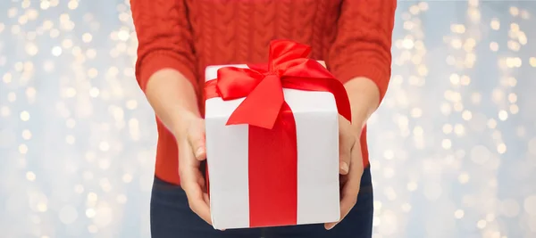 Крупным планом женщина в красном свитере держит подарочную коробку — стоковое фото