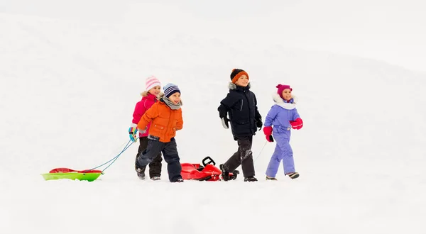 Petits enfants heureux avec des traîneaux en hiver — Photo