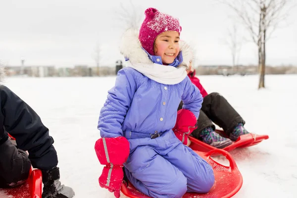 Niña en platillo de nieve trineo en invierno —  Fotos de Stock