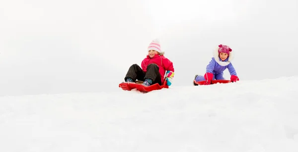 Ragazze che scivolano su slitte giù collina di neve in inverno — Foto Stock