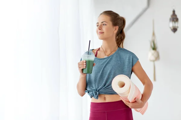 Donna con tazza di frullato e stuoia allo studio di yoga — Foto Stock