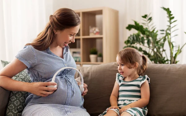 Pregnant mother and little girl with headphones — Stock Photo, Image