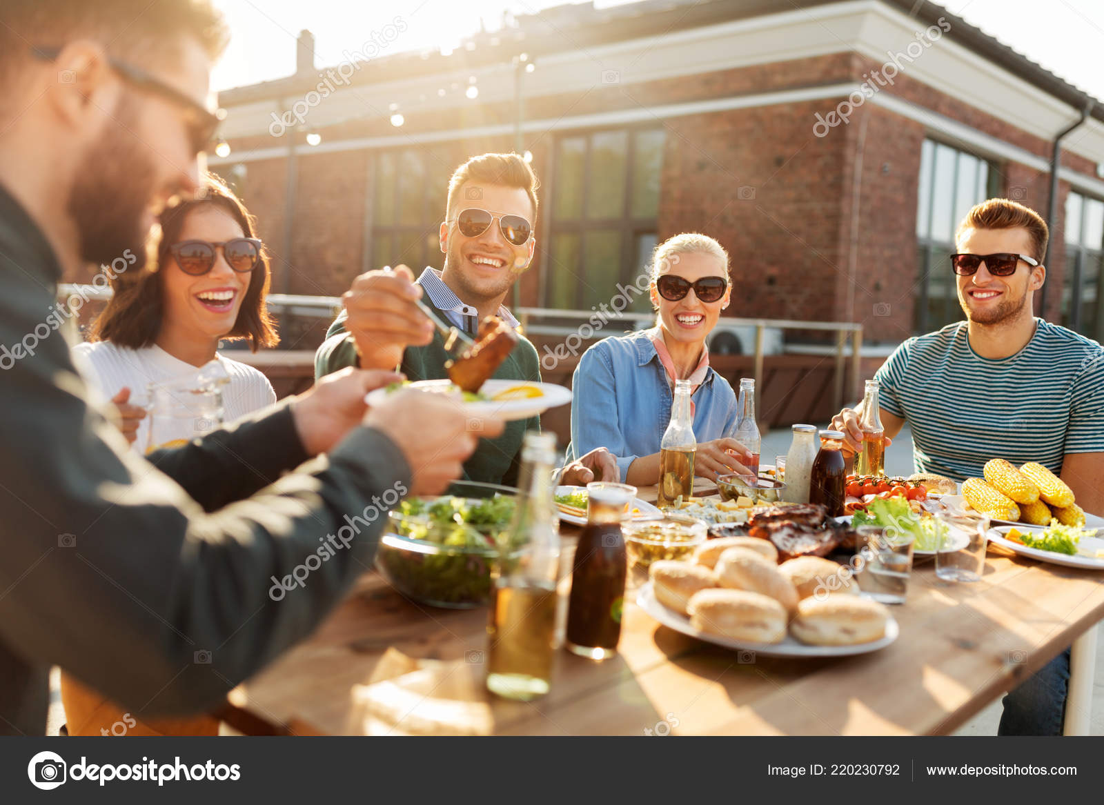 Friends having dinner or bbq party on rooftop Photo by ©Syda_Productions 220230792