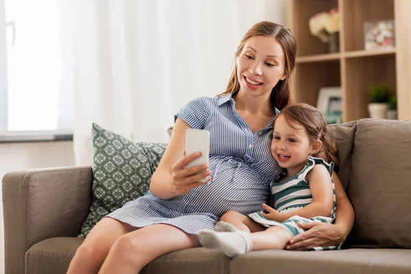 Mère enceinte et fille avec smartphone — Photo