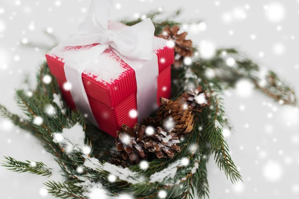 Рождественский подарок и еловый венок с шишками на снегу — стоковое фото