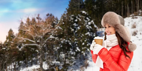 Žena v kožešinovou čepici s kávou nad zimní les — Stock fotografie