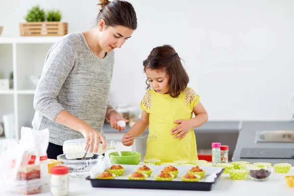 Mãe feliz e filha assar muffins em casa — Fotografia de Stock