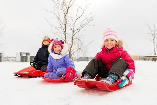 Crianças pequenas felizes que deslizam em trenós no inverno — Fotografia de Stock
