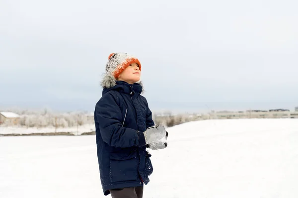 Glücklicher kleiner Junge, der im Winter mit Schnee spielt — Stockfoto