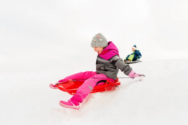 Щаслива маленька дівчинка ковзає на санчатах взимку — стокове фото