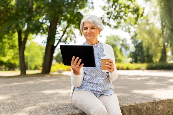 Old woman with tablet pc and coffee at summer park — Stock Photo, Image