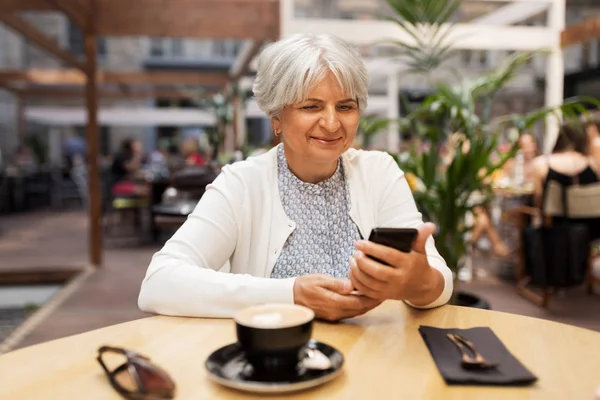 Glückliche Seniorin mit Smartphone im Straßencafé — Stockfoto