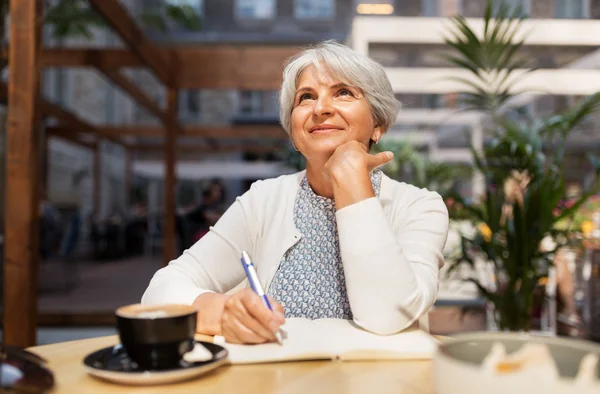 Donna anziana con notebook che sogna al caffè di strada — Foto Stock