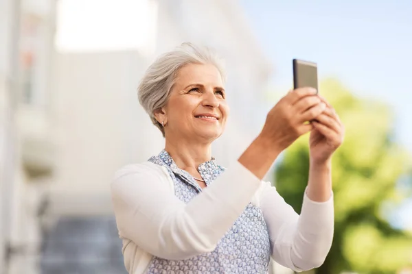 Senior vrouw fotograferen door smartphone in stad — Stockfoto
