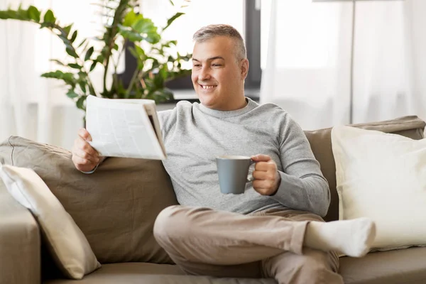Чоловік читає газети і п'є каву вдома — стокове фото