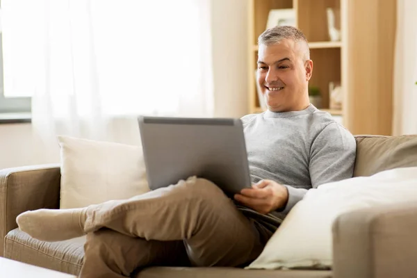 Mann mit Laptop sitzt zu Hause auf Sofa — Stockfoto
