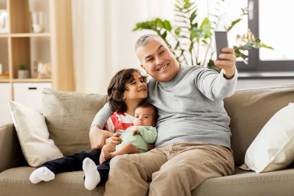 Pai feliz com filhos tomando selfie em casa Imagens Royalty-Free