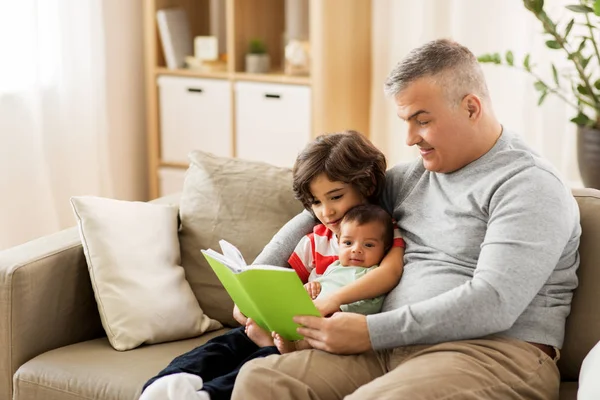 Feliz padre con hijos leyendo libro en casa — Foto de Stock