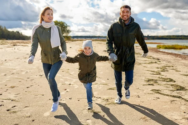 Gelukkige familie loopt langs herfst strand — Stockfoto