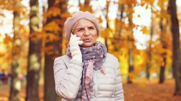 Femme âgée appelant sur smartphone au parc d'automne — Video
