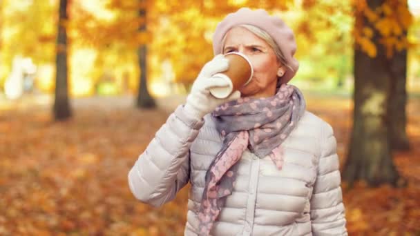 Senior woman drinking coffee in autumn park — Stock Video