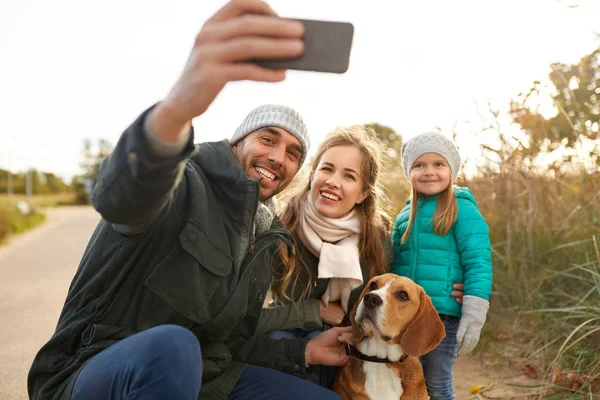 happy family with dog taking selfie in autumn