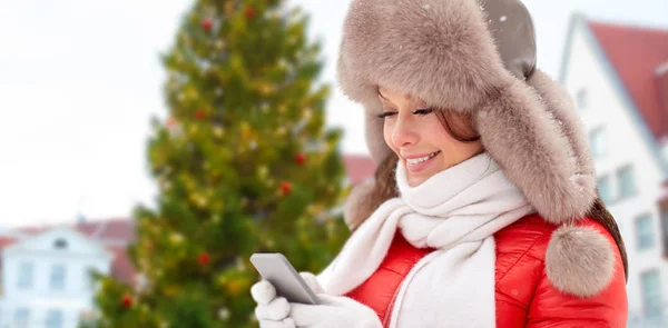 Woman with smartphone over christmas tree — Stock Photo, Image