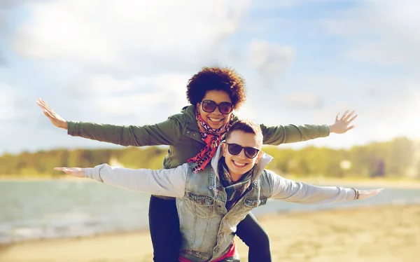 Happy teenage couple in shades having fun on beach — Stock Photo, Image