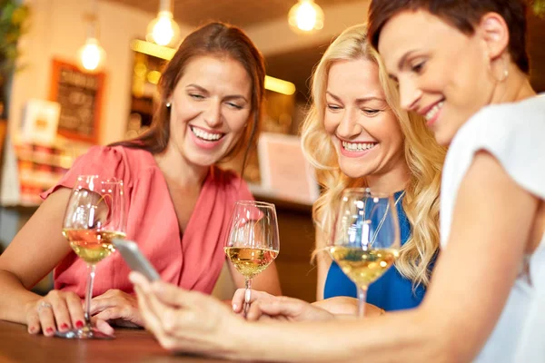 Kvinnor med smartphone på vin bar eller restaurang — Stockfoto