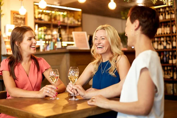 happy women drinking wine at bar or restaurant