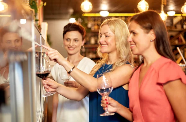 Happy women pouring wine from dispenser at bar — Stock Photo, Image
