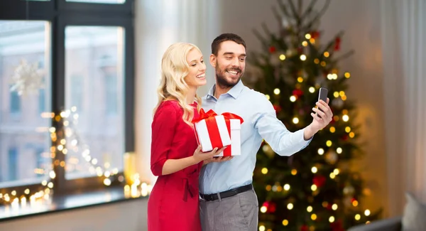 Пара делает селфи на смартфоне на Рождество — стоковое фото