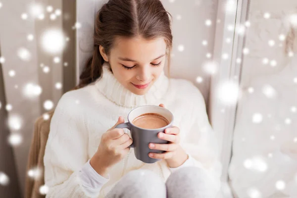 Flicka i vinter tröja med cacao mugg på fönster — Stockfoto