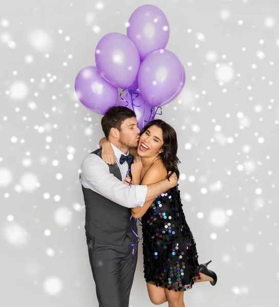 Feliz pareja con violeta globos besándose en la fiesta — Foto de Stock