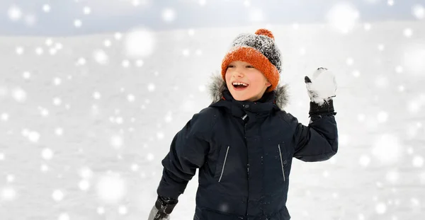 Niño feliz jugando y lanzando bola de nieve en invierno — Foto de Stock