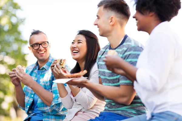 Amigos felices comiendo sándwiches y pizza al aire libre —  Fotos de Stock