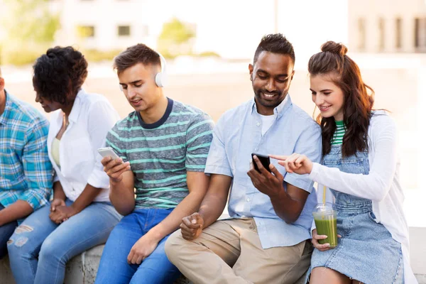 Vrienden met smartphones opknoping in de zomer — Stockfoto