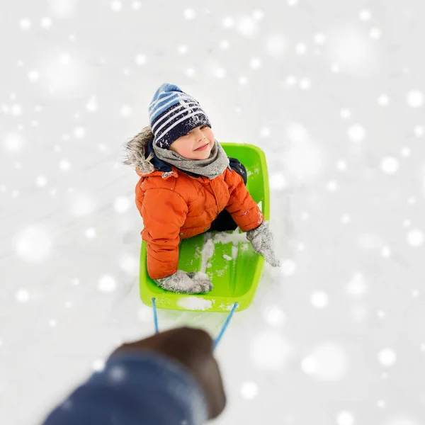 Heureux garçon équitation traîneau sur la neige en hiver — Photo