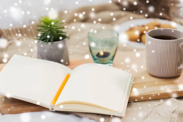 Diary, tea and candle in holder at home over snow — Stock Photo, Image